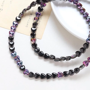 Macro shot of iridescent purple and black heart-shaped glass beads for jewelry making