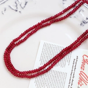 Detailed view of faceted dark red agate beads strand on a vintage white ceramic plate