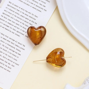 Dettaglio macro di perline a cuore in vetro ambrato con foglia d'oro per gioielli fai da te