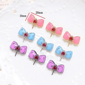 Macro detail of 20x10mm heart gemstone bow pendants in pink, blue, and purple tones