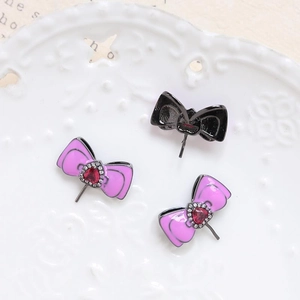 Macro detail of bow-shaped jewelry pins with red heart gems and sparkling rhinestone accents