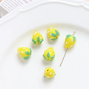Detailed view of yellow glaze strawberry beads with needle for DIY jewelry making