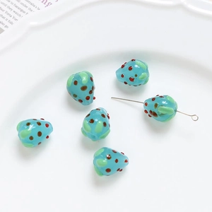 Macro shot of blue glass strawberry beads with red dots for DIY jewelry making