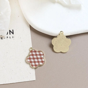 Detail of flower charm with red gingham pattern and golden metal back for DIY jewelry