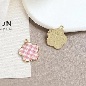 Macro view of flower pendant with pink and white checkered pattern and gold metallic back
