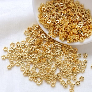 Detailed view of 14k gold-filled plum blossom spacers on white silk for jewelry making