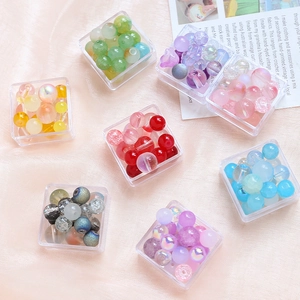 Close-up of assorted glass beads in storage boxes on a soft satin fabric for DIY jewelry