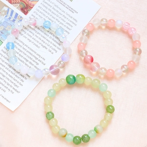Three DIY beaded bracelets in blue, pink, and green colors on soft fabric background