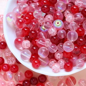 Detail of red and pink DIY crackle glass beads with AB coating in a white ceramic bowl