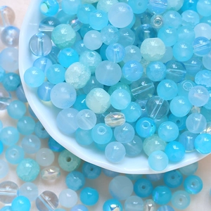 Macro detail of mixed blue DIY beads with ice crackle and aurora luster in a ceramic bowl