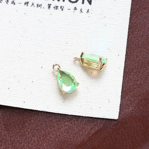 Macro detail of two green pear-shaped crystal pendants with gold claw settings for DIY jewelry