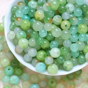 Close-up of green cracked glazed glass beads in a white bowl for DIY jewelry