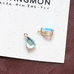 Macro shot of two pear-shaped teardrop zircon pendants with rainbow blue-green gradient finish