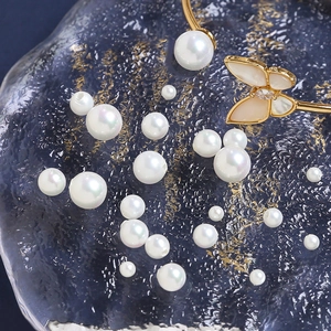 Macro view of high-gloss pearls and golden butterfly jewelry component on glass