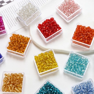 Detailed top view of 4mm colorful glass seed beads sorted in clear plastic boxes