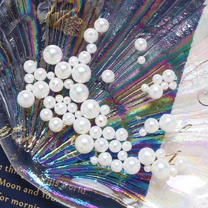 Lustrous white round DIY craft pearls with pre-drilled holes in a shell tray