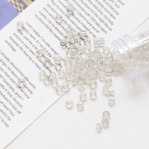 Macro shot of 4mm glass gold foil beads with silver cores spilled from a clear bottle
