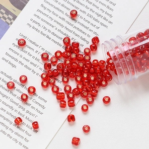 Macro shot of 4mm red glass beads with silver core spilling from a jar for DIY jewelry
