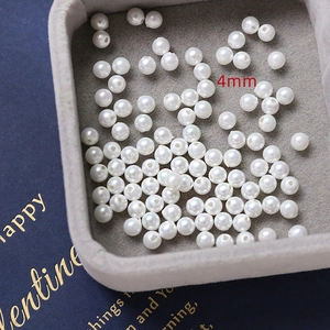 Macro view of 4mm white high-luster loose pearls for DIY jewelry making on grey tray