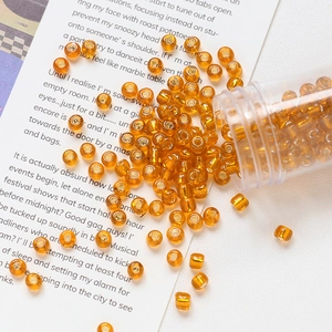 Macro view of 4mm amber glass seed beads in a plastic tube for DIY jewelry making