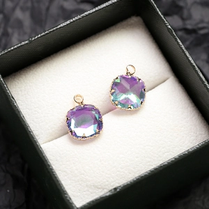 Détail de pendentifs en cristal carré avec dégradé violet et monture dorée à griffes