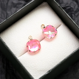 Vue macro de deux pendentifs en cristal rose avec griffes dorées dans un écrin à bijoux