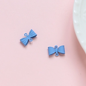 Detailweergave van lichtblauwe strikbedeltjes voor doe-het-zelf sieraden op roze