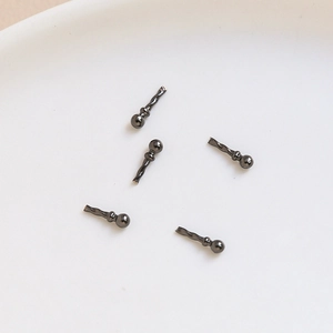 Detailed close-up of five gun black metal craft pins in a white dish for jewelry making
