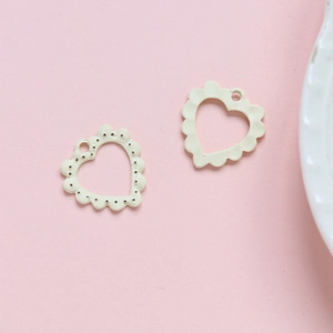 Macro-opname van hartvormige crèmekleurige hangers met golvende randen voor DIY-sieraden