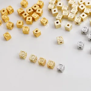 Detailed macro view of 4mm gold and silver square smiley face beads for DIY jewelry