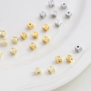 Gold and silver smile face cube spacer beads for DIY jewelry making on white tray