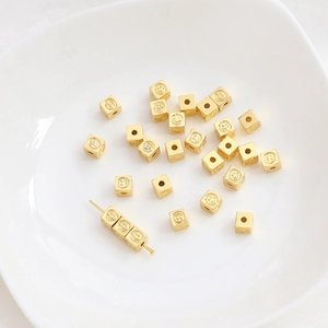 Detailed macro view of 14K gold-plated square smile face spacer beads for DIY jewelry