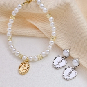Detailed shot of vintage gold rose pendant set with pearl bracelet and heart earrings
