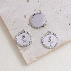 Macro detail of silver rose relief charms with wavy borders for DIY jewelry making