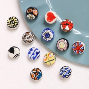 Macro shot of hand-painted ceramic beads with heart and floral patterns for DIY jewelry