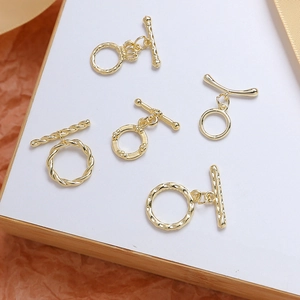 Détail de cinq fermoirs OT dorés pour la fabrication de bijoux DIY sur carte blanche