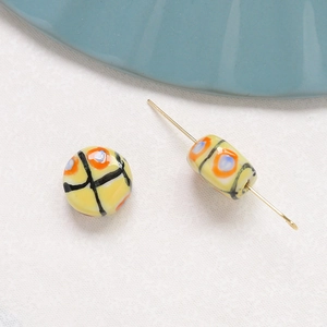 Close-up of yellow ceramic beads with black plaid and colorful hand-painted dots for DIY
