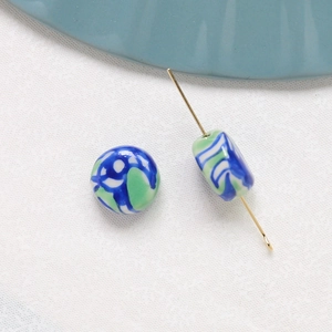Detailed macro view of hand-painted blue and green floral ceramic beads for DIY jewelry