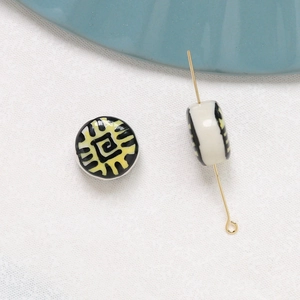Close-up of vintage ceramic beads with black and yellow abstract patterns on white fabric