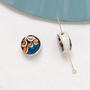 Detail of hand-painted ceramic beads with ocean wave patterns and gold pin for DIY jewelry