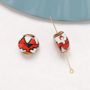 Detail of hand-painted ceramic beads with abstract red and black floral patterns for DIY