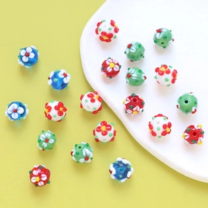 DIY floral glass beads for jewelry making in assorted colors on ceramic plate