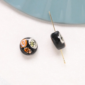 Macro detail of hand-painted floral ceramic beads on white fabric for DIY jewelry making