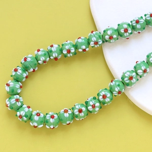Macro shot of green lampwork glass floral beads with detailed white petals for DIY jewelry