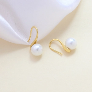 Ganchos para pendientes bañados en oro con perlas blancas sobre fondo de seda suave