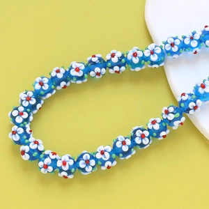 Macro shot of blue glass flower beads with intricate floral patterns for DIY jewelry