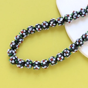 Close-up of millefiori glass flower beads with black base and colorful floral patterns