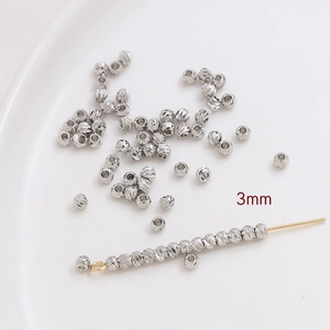 Vista detallada de cuentas plateadas de 3mm con textura para creación de joyería DIY