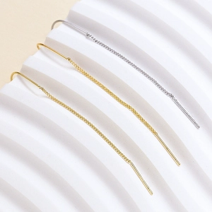 Minimalist long threader earrings in gold and silver finish on a white textured stand