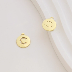 Macro view of gold-plated circular letter C pendant with sparkling cubic zirconia inlay